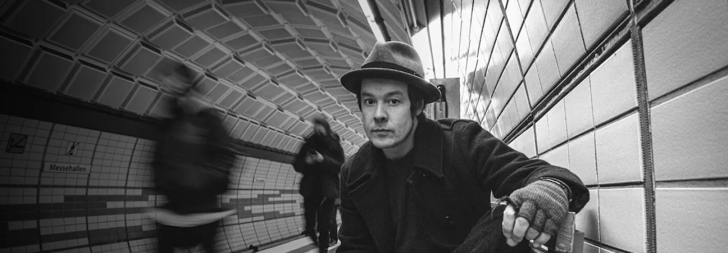 black and white portrait of jon sitting in the subway station on a bench